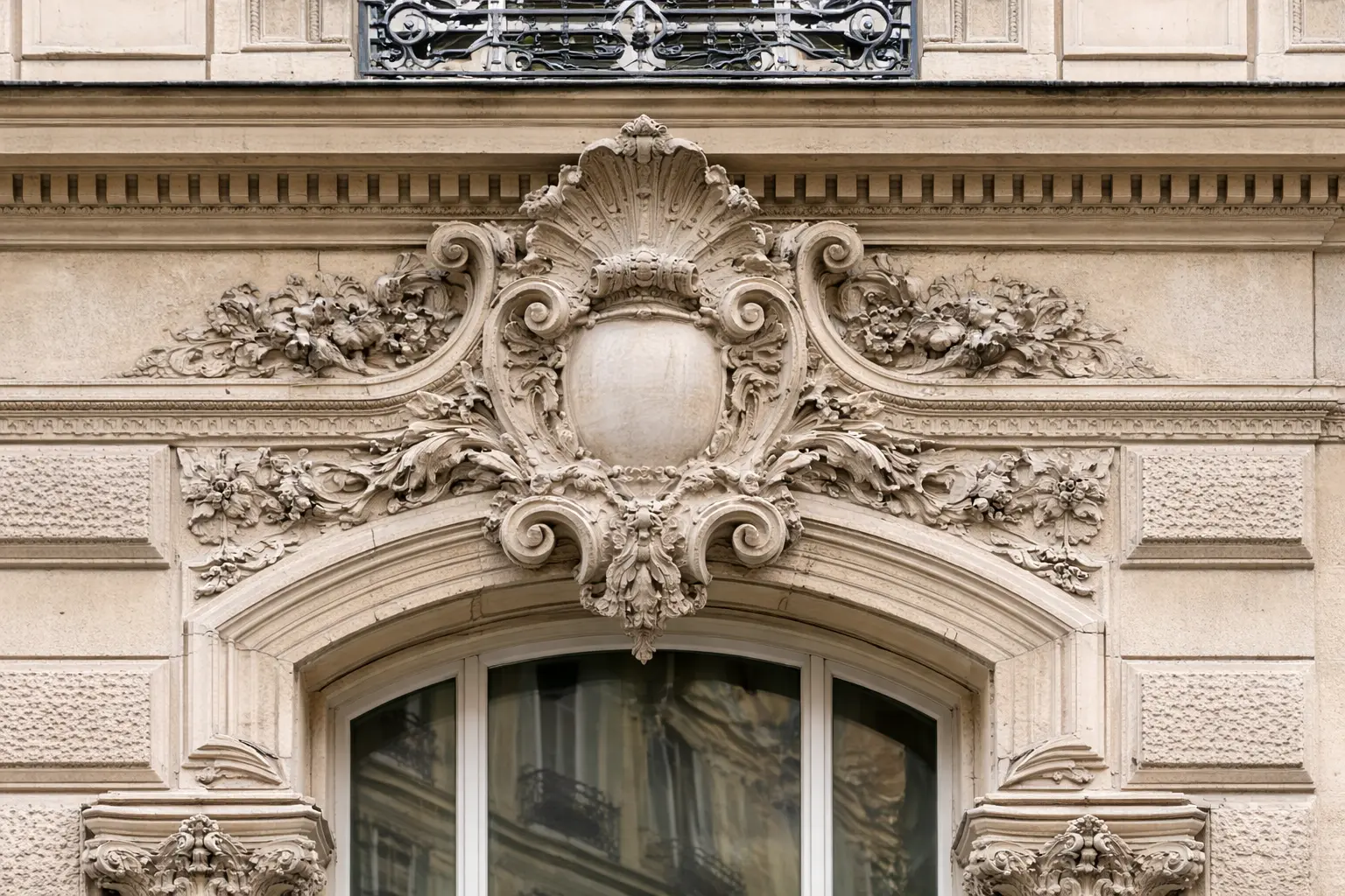 Isolamento Involucro edificio: dettaglio di fregio decorativo su di palazzo storico con elementi floreali e cornice ornamentale sopra una finestra, isolabile solo con un prodotto come Manti Ceramic