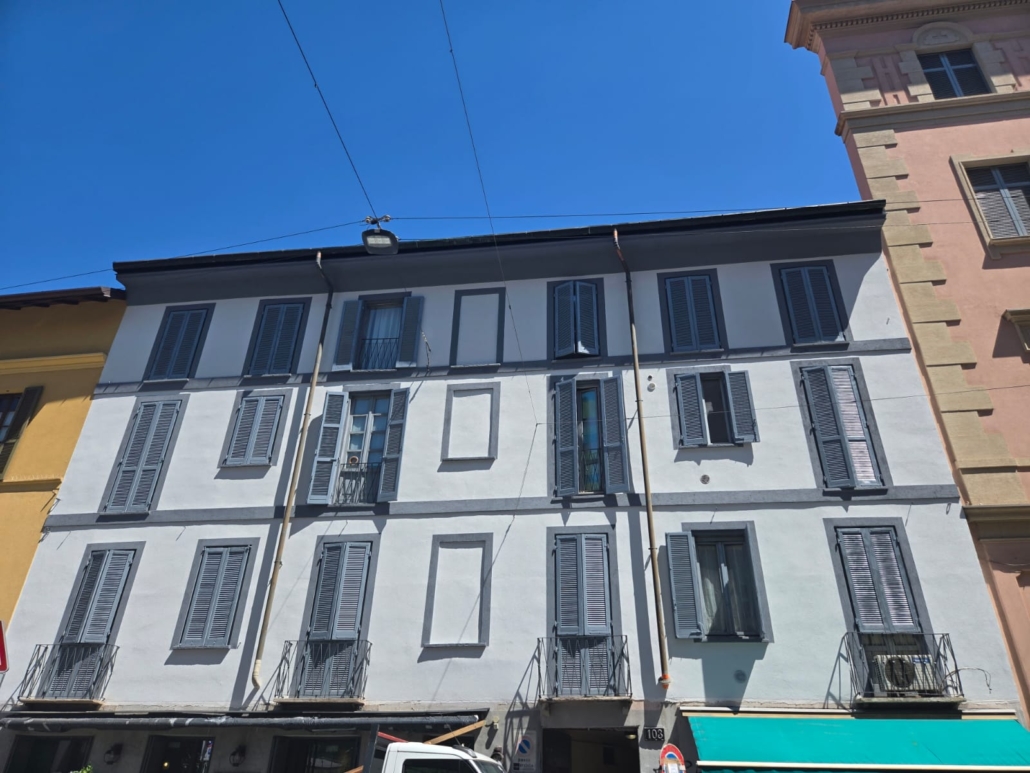 Facciata storica di edificio residenziale a Milano dopo intervento di isolamento a basso spessore con marcapiani e cornici in rilievo mantenuti visibili
